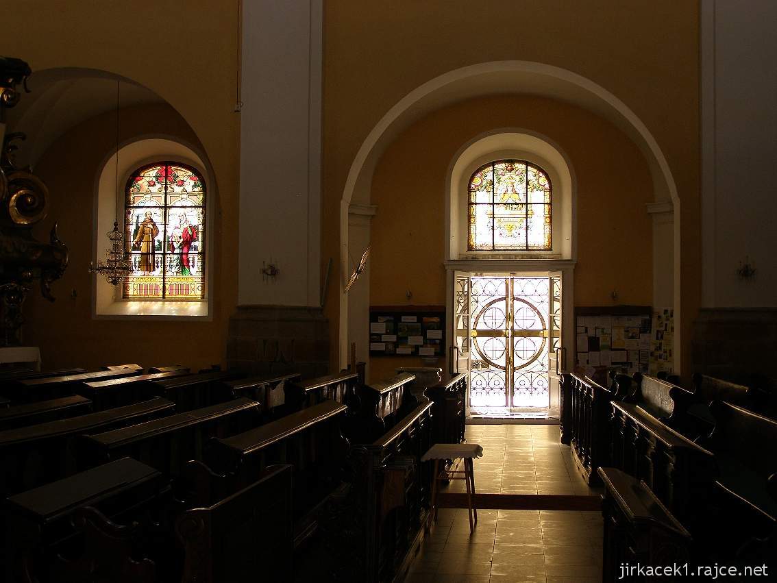 Nový Jičín - kostel Nanebevzetí Panny Marie - kostelní lavice, vitrážové okna a boční vchod