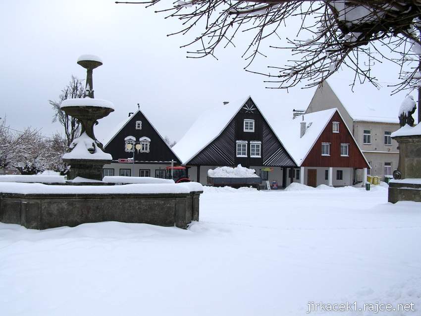 Rokytnice v Orlických horách - náměstí T.G. Masaryka - renesanční kašna a roubené domy ve spodní části náměstí v zimě